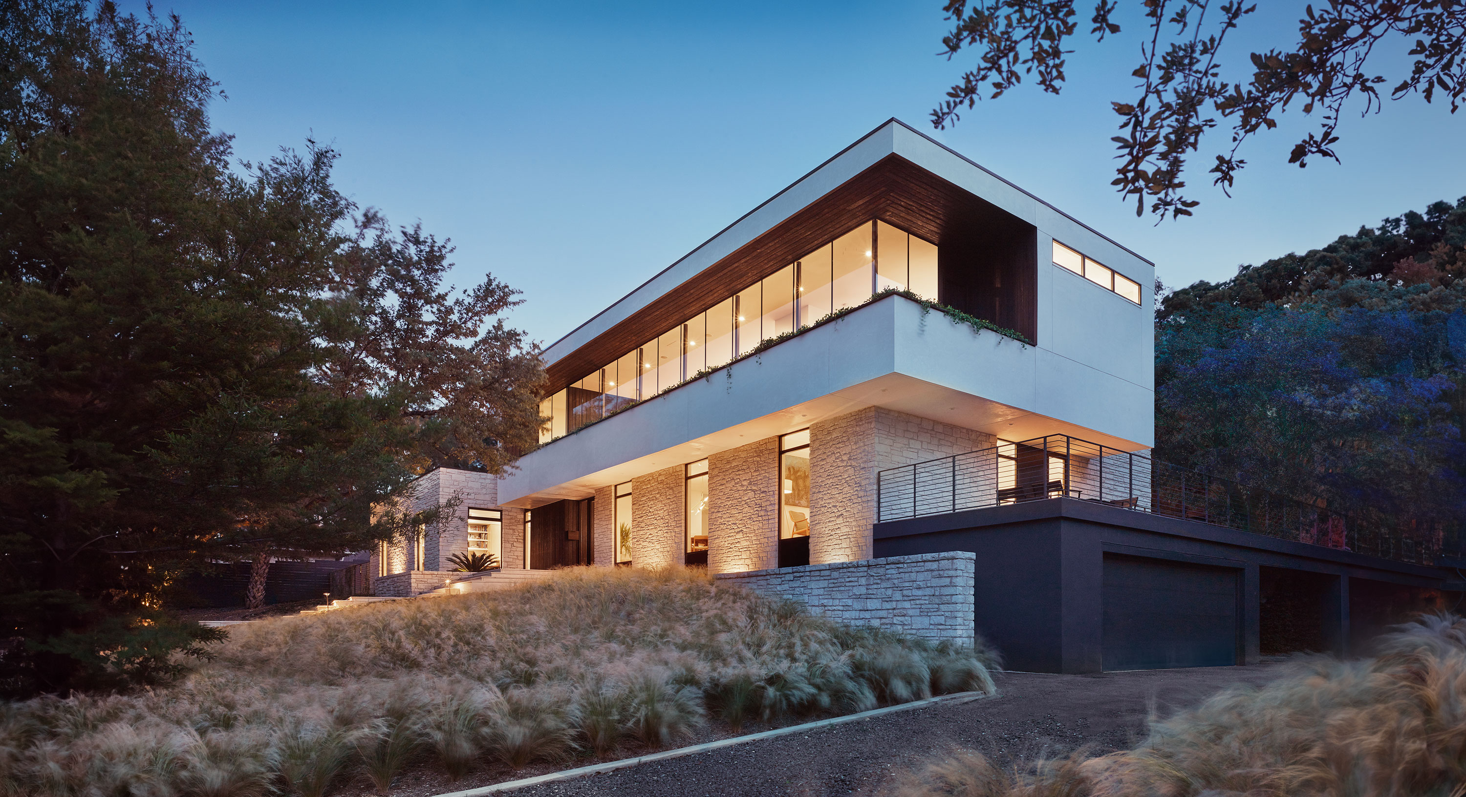 Exterior photo of the Treetops House residence by Specht Novak Architects. Shot by Casey Dunn, featuring frameless glass windows, cantilever, and limestone perimeter wall.