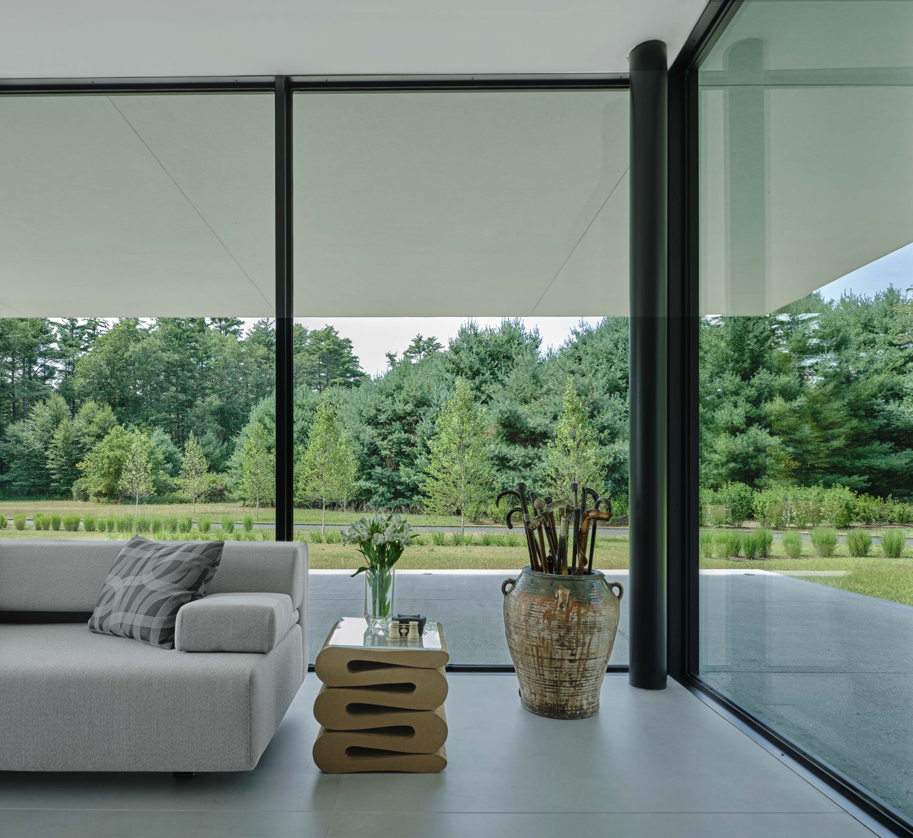 Interior photo of the Casa Annunziata Residence by Specht Novak Architects. Shot by Dror Baldinger, featuring a living space enclosed in glass walls displaying the lush greenery that surrounds the home.