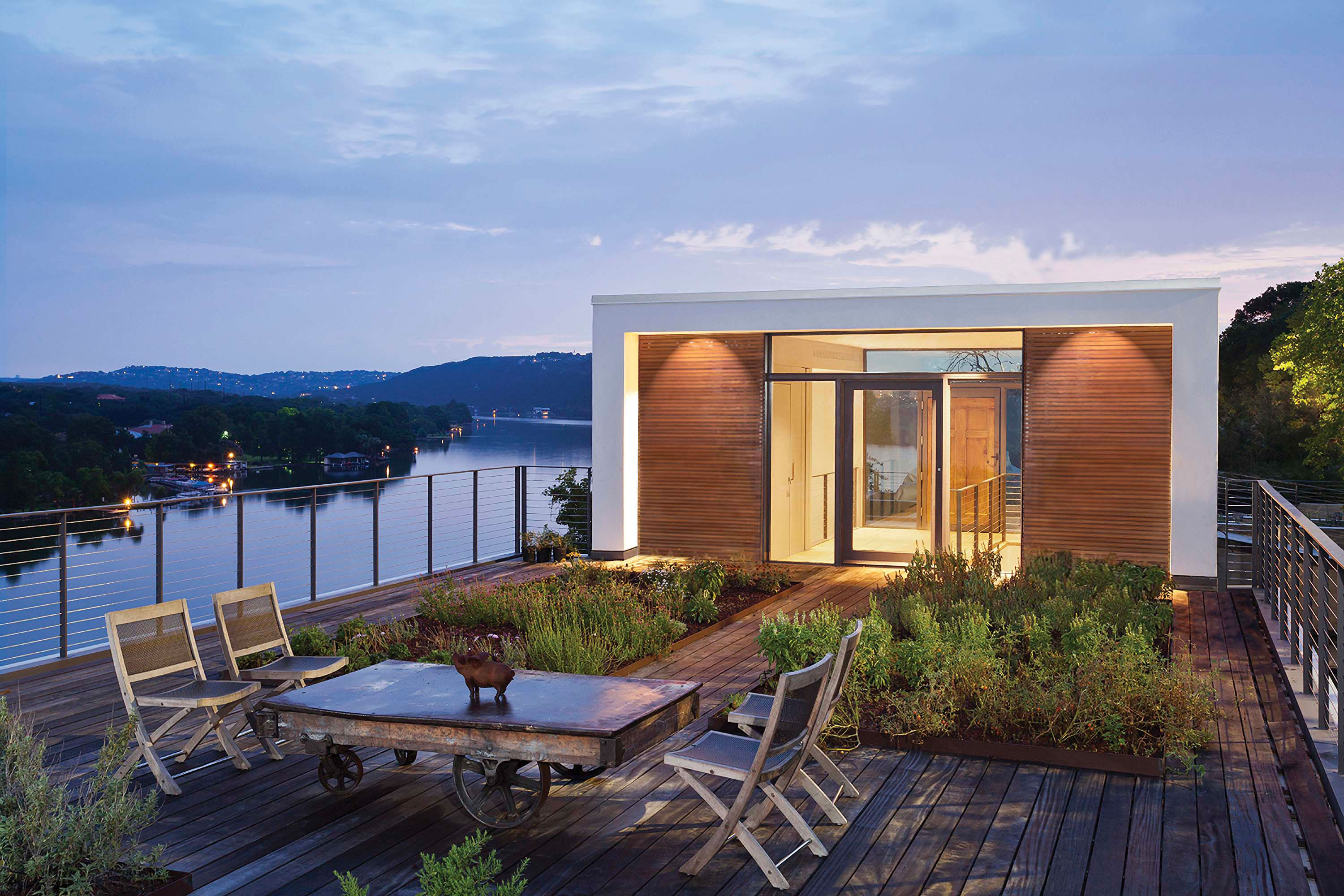 Exterior photo of the Cliffside Residence by Specht Novak Architects. Shot at dusk by Andrea Calo, featuring a courtyard that leads the way into symmetrical entry of the home, overlooking Lake Austin.