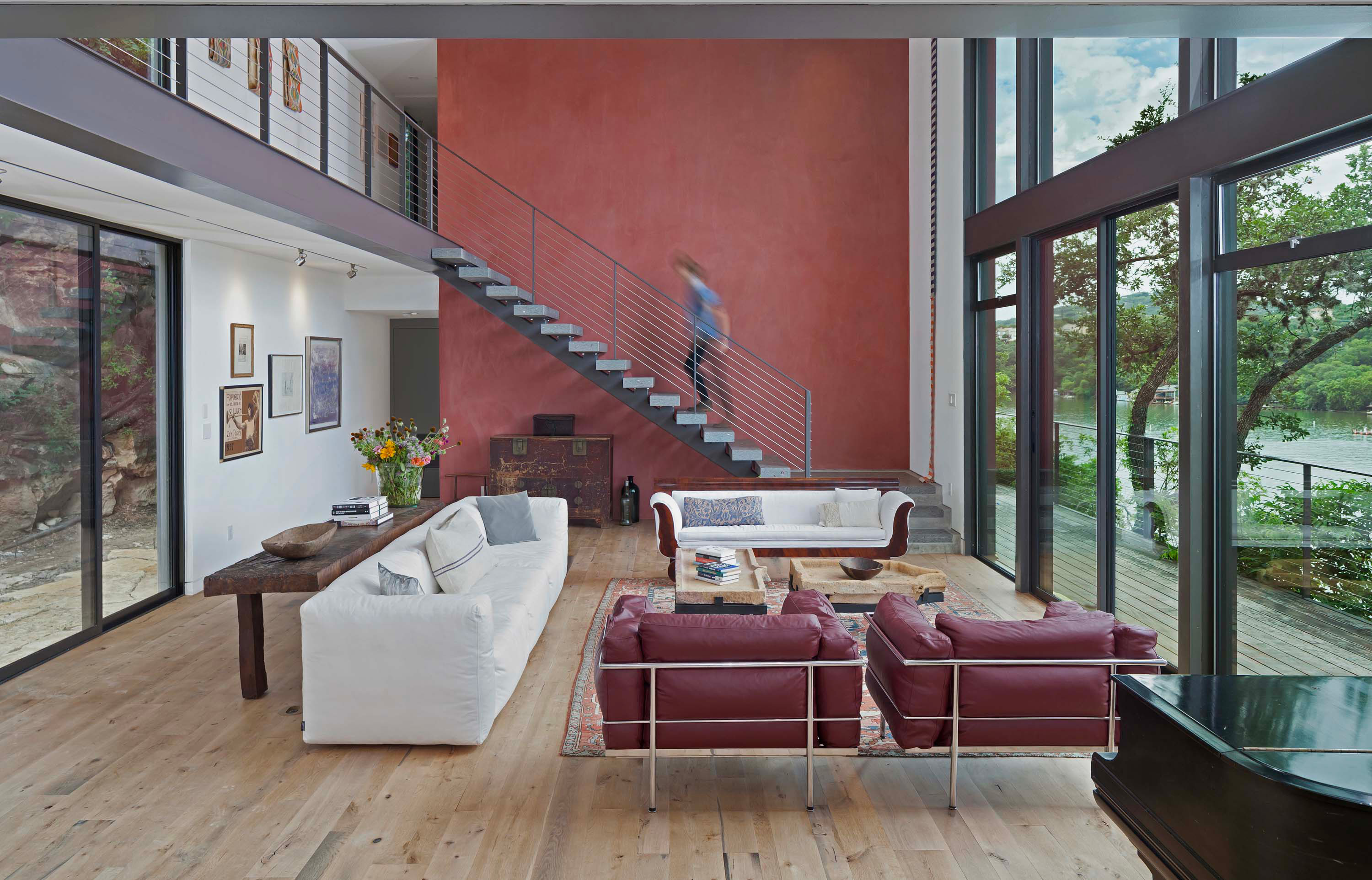 Exterior photo of the Cliffside Residence by Specht Novak Architects. Shot Andrea Calo, featuring a living area, with steel, wooden, and concrete details, a glass wall that brightens the room, and a red accent wall.
