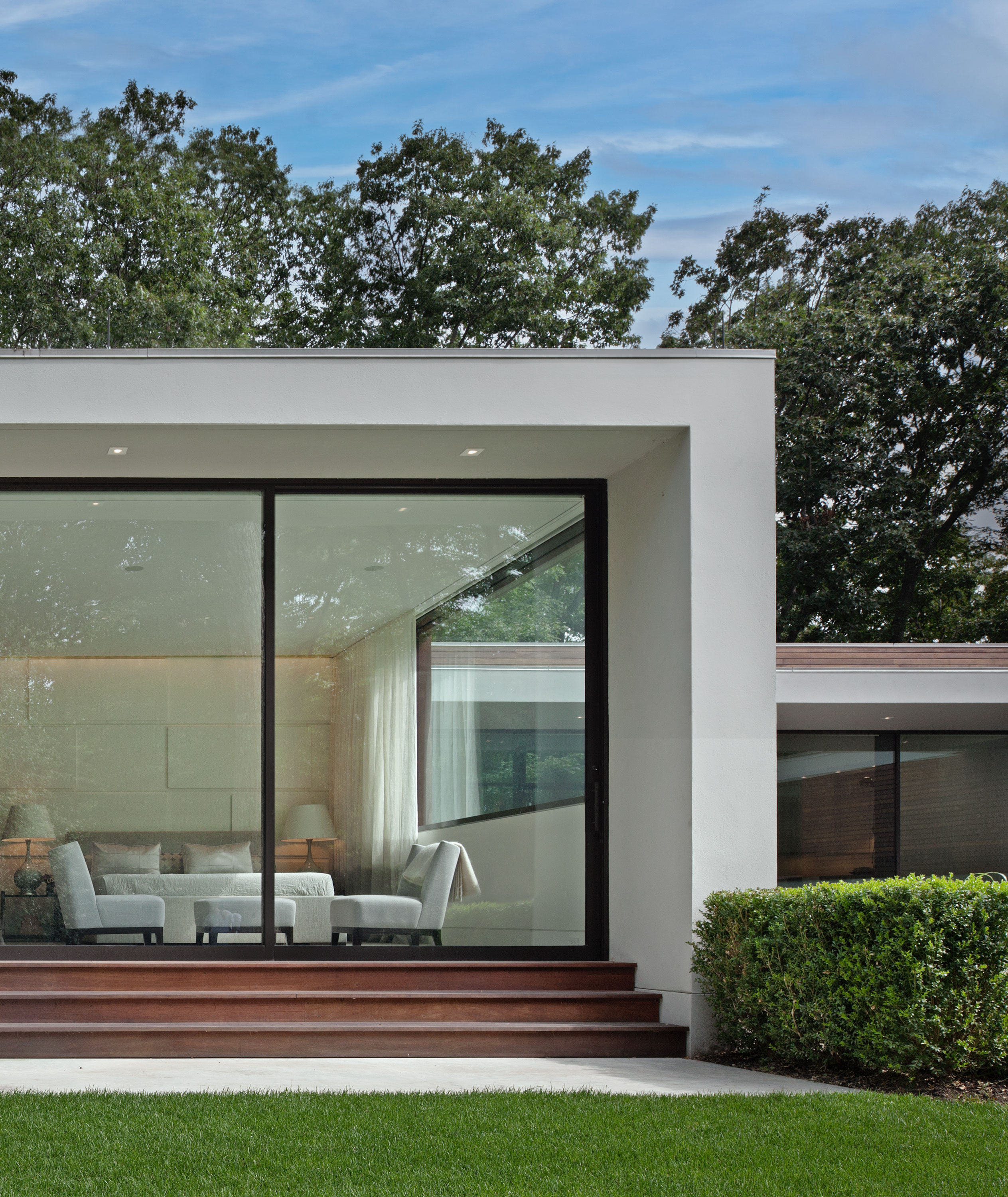 Exterior photo of the New Canaan Residence by Specht Novak Architects. Shot at dusk by Elizabeth Felicella featuring the simple geometric structure of the home highlighted by its concrete and glass walls.