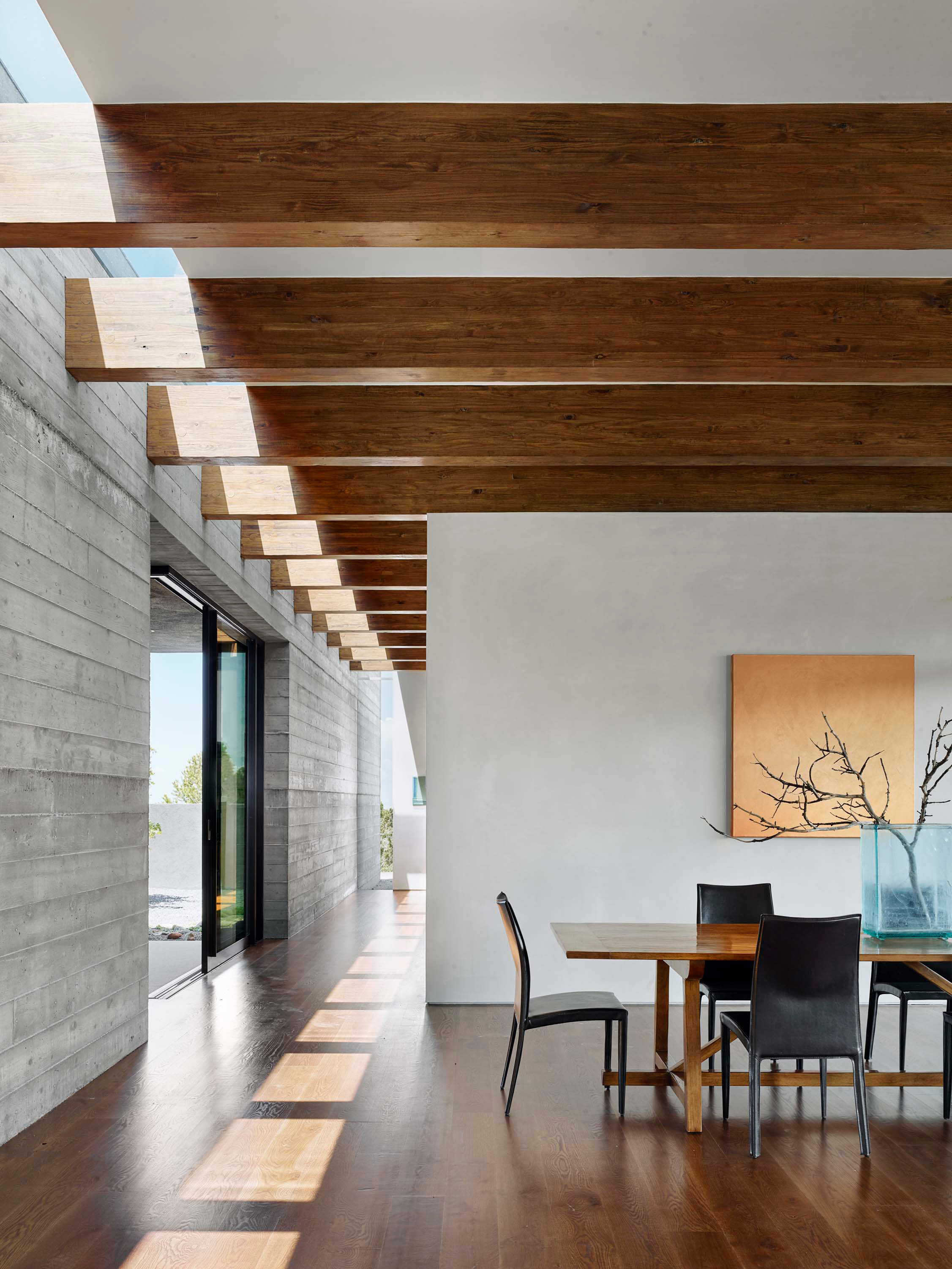 Interior photo of the Sangre de Cristo House by Specht Novak Architects. Shot by Casey Dunn, featuring a dining area with wooden floors, beamed ceilings, and longitudinal hallway.