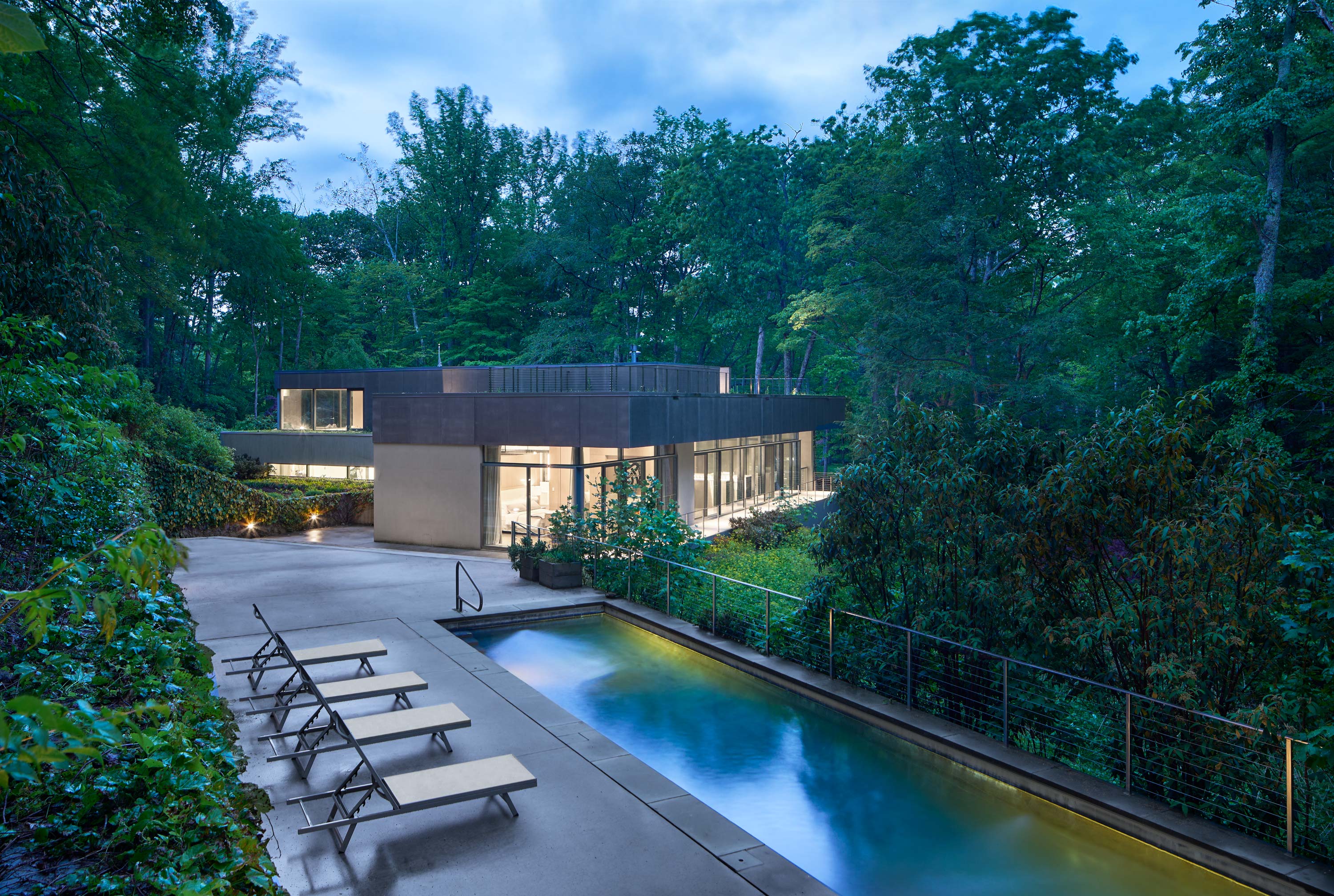 Exterior photo of Weston Residence by Specht Novak Architects. Shot by Jasper Lazor, featuring the concrete and glass home with roof gardens, and outside pool with lounging area.