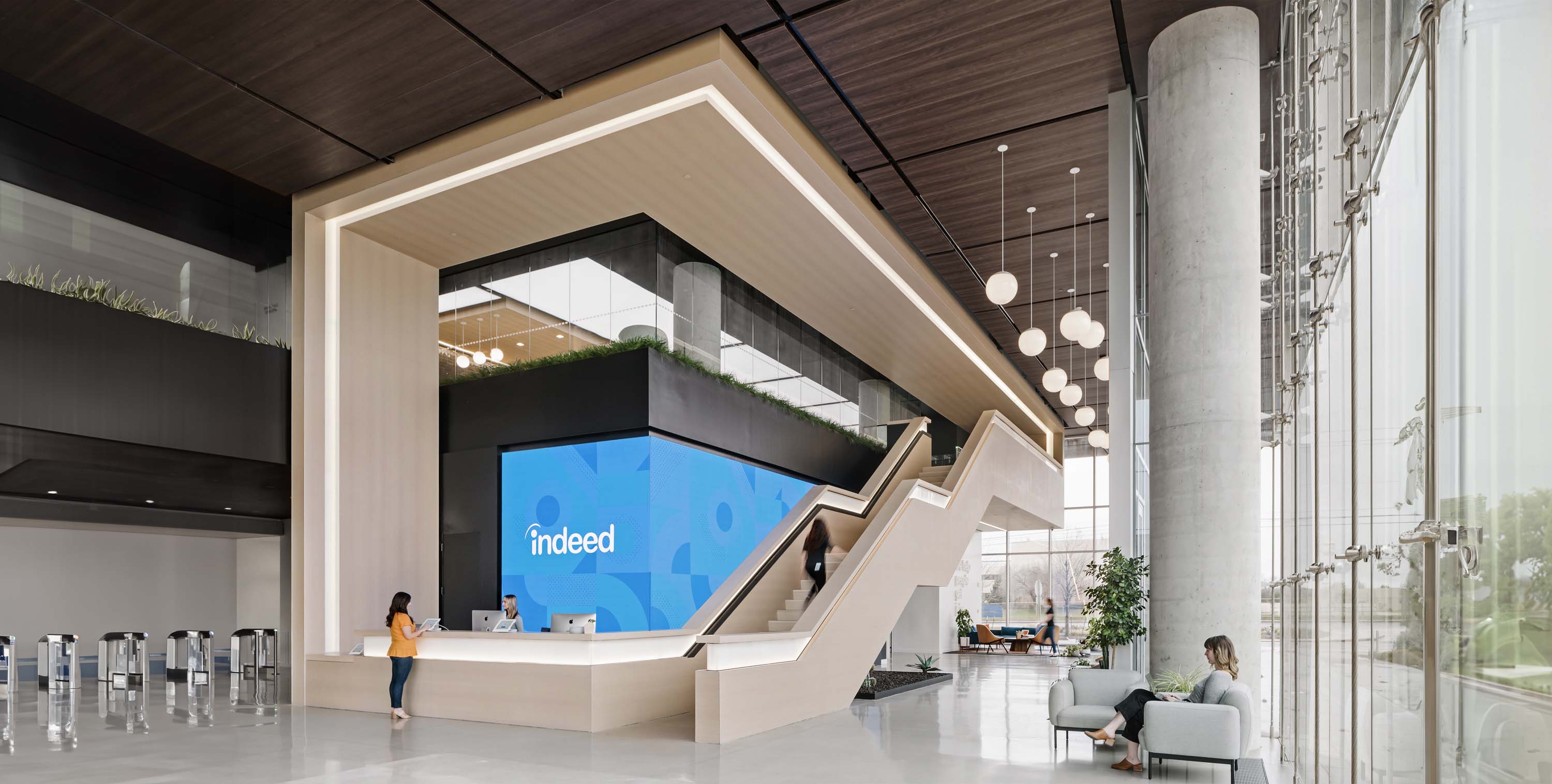 Indeed.com in Austin, Texas by Specht Novak Architects, shot by Andrea Calo, framed by desk and staircase showcasing cool toned materials and open floorplan.