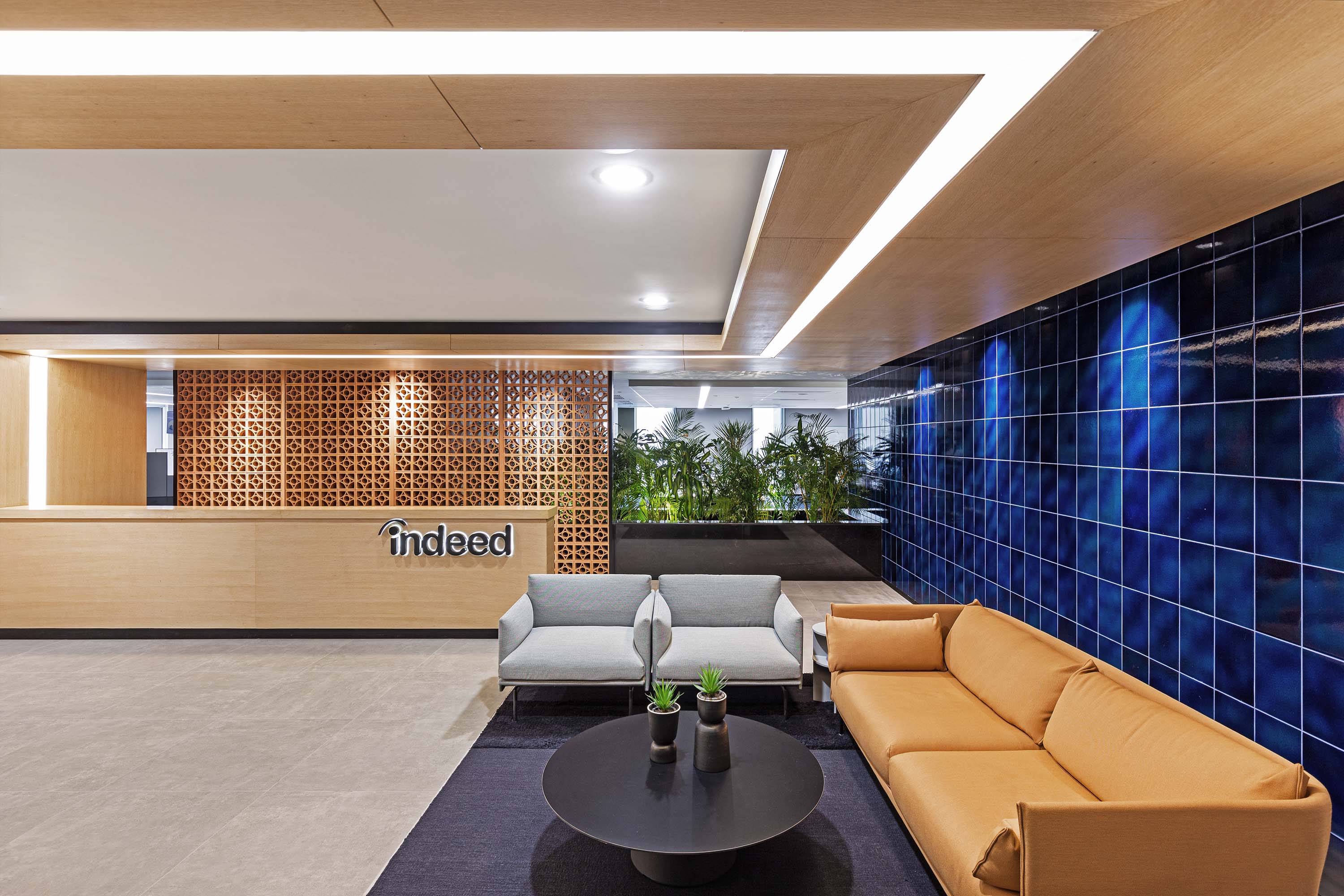 Reception waiting area of Indeed.com by Specht Novak Architects featuring blue tiled wall and wood accents.