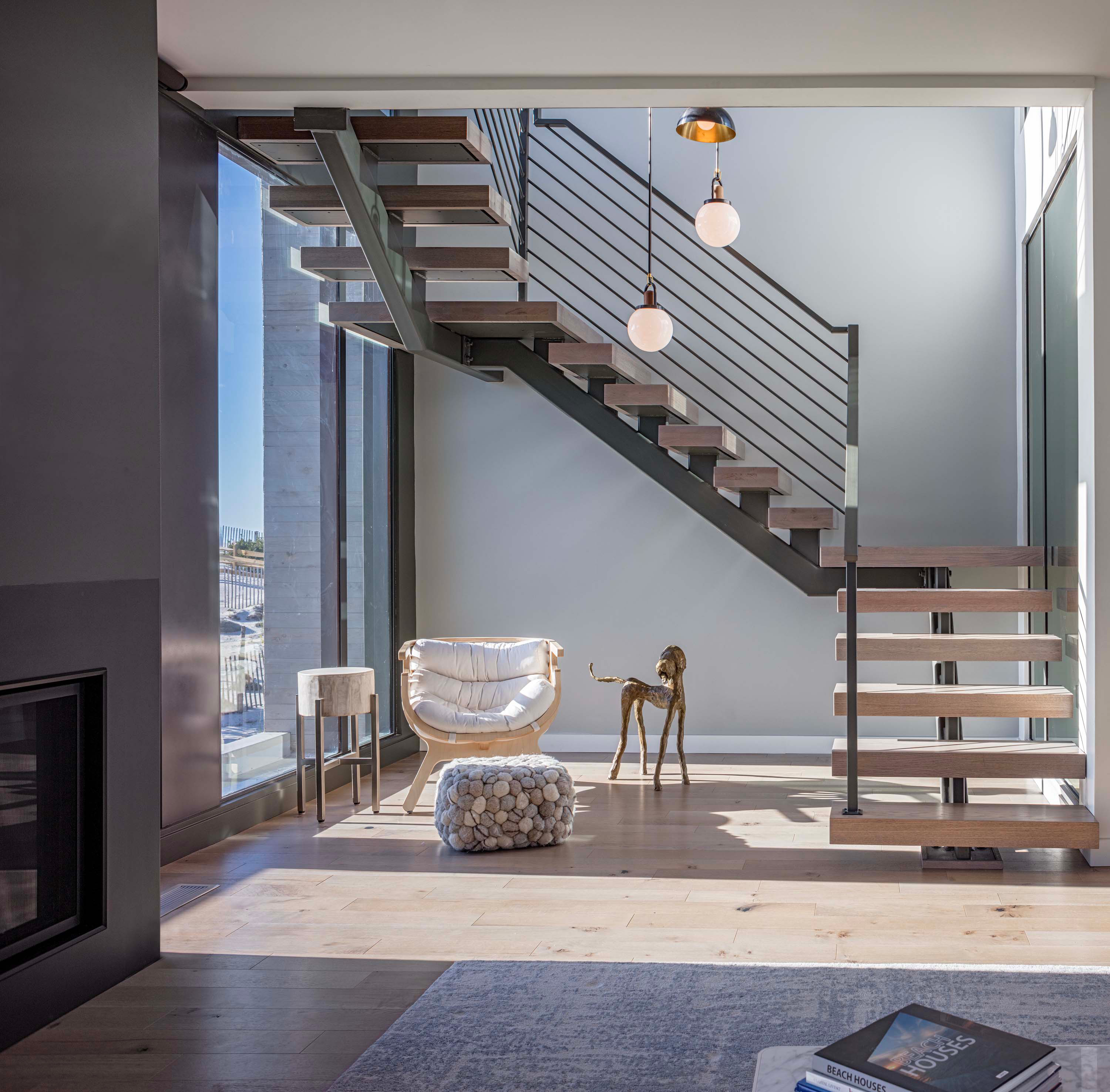Interior photo of the Beach Haven Residence by Specht Novak Architects. Shot by Taggart Sorenson featuring brightly illuminated stairs and lounging area below them.