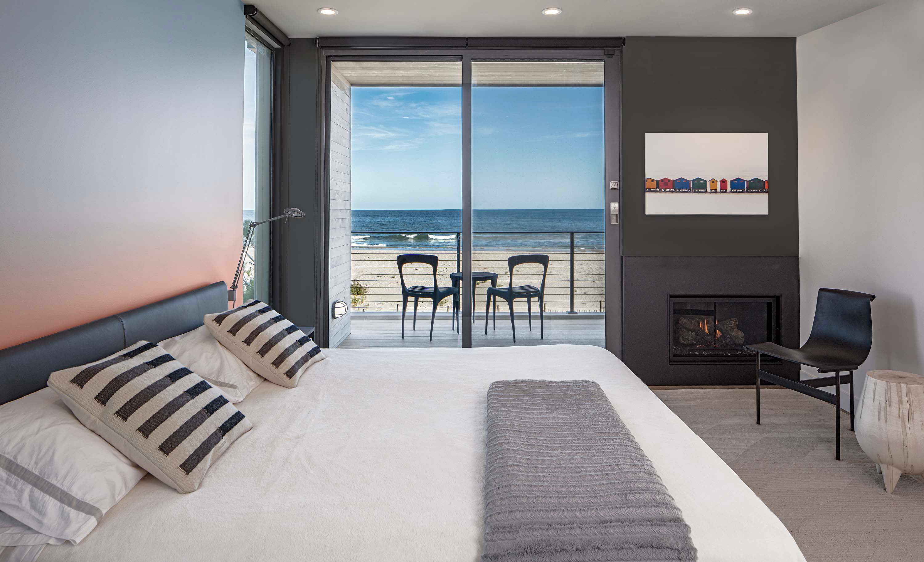 Interior photo of the Beach Haven Residence by Specht Novak Architects. Shot by Taggart Sorenson featuring a bedroom with large glass sliding doors that open to a balcony and view of the beach.