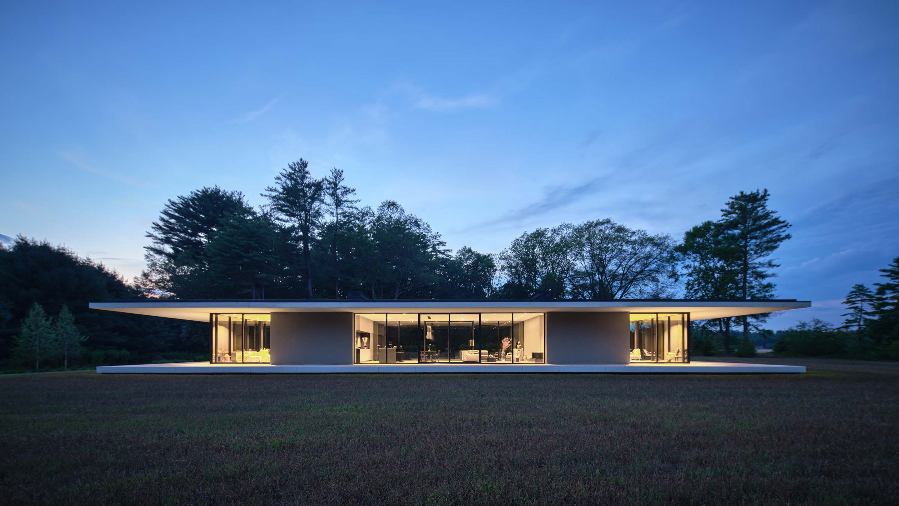 Exterior photo of the Casa Annunziata Residence by Specht Novak Architects. Shot at dusk by Dror Baldinger featuring the symmetrical single-story pavilion with a thin floating roof that cantilevers 15’ from the perimeter walls.