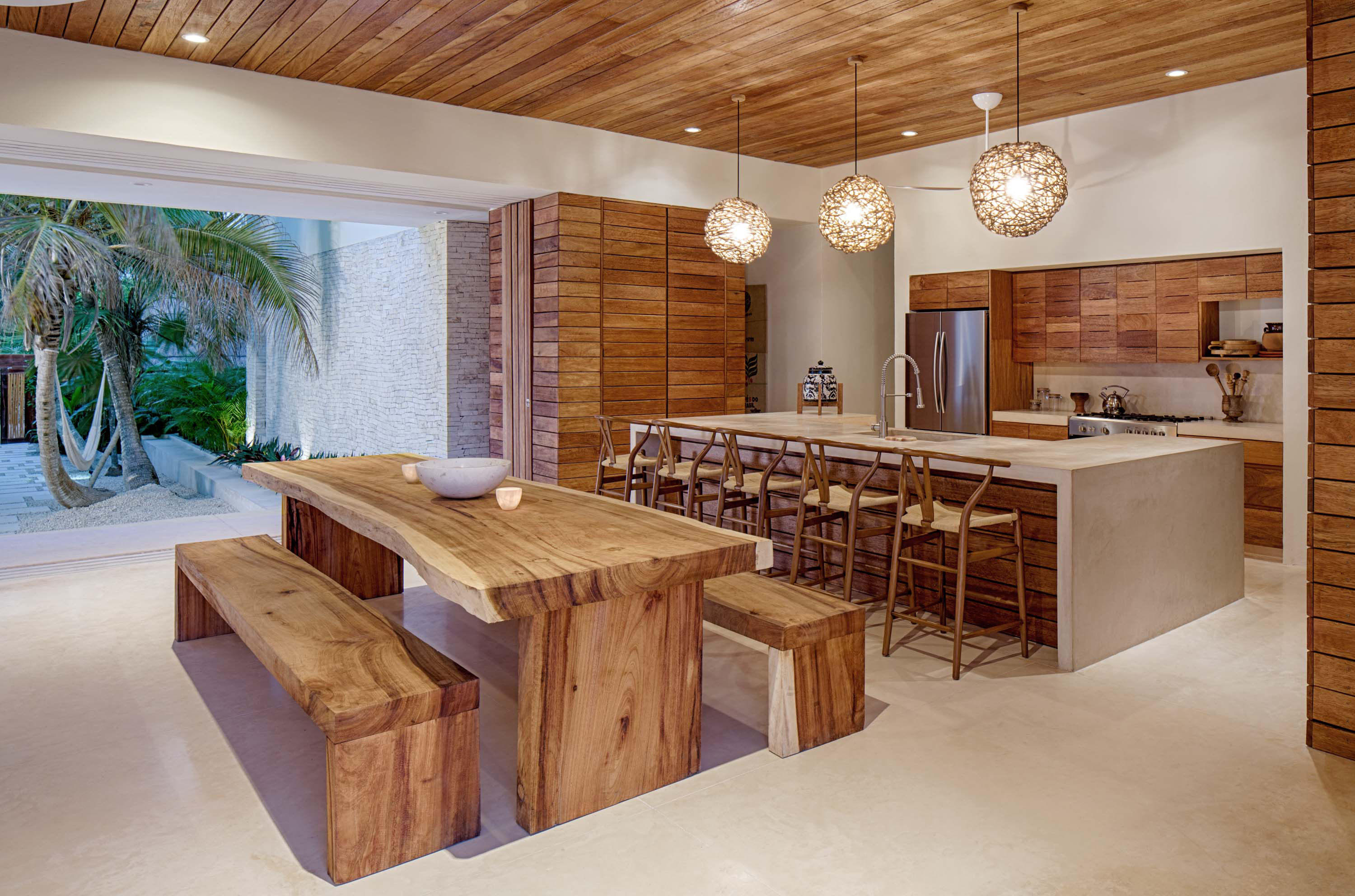 Interior photo of Casa Xixim by Specht Novak Architects. Shot by Taggart Sorensen, featuring an island kitchen with wooden accents and adjacent dining area.