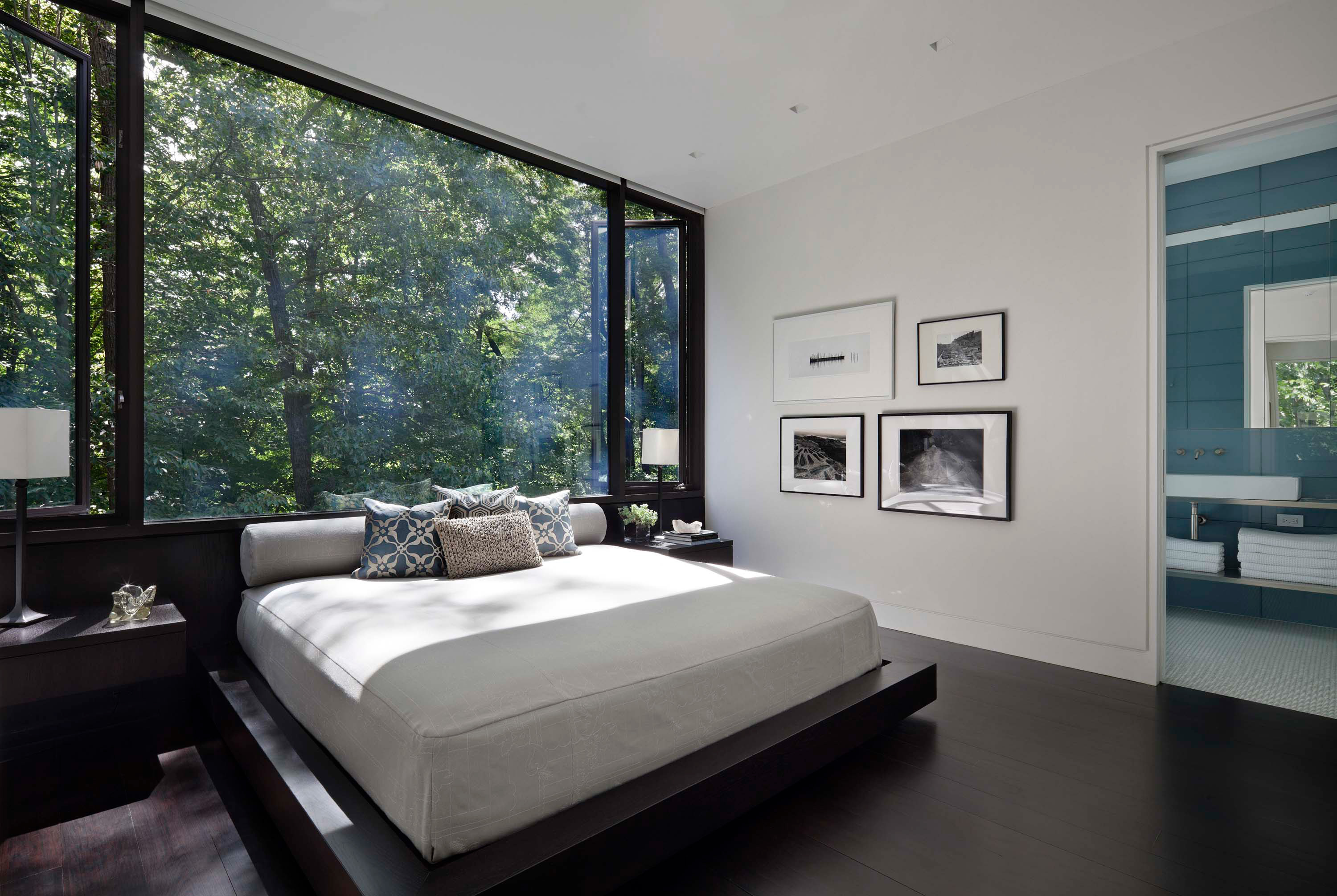 Interior photo of the New Canaan Residence by Specht Novak Architects. Shot by Elizabeth Felicella featuring a bedroom with a main glass wall and ensuite bathroom.