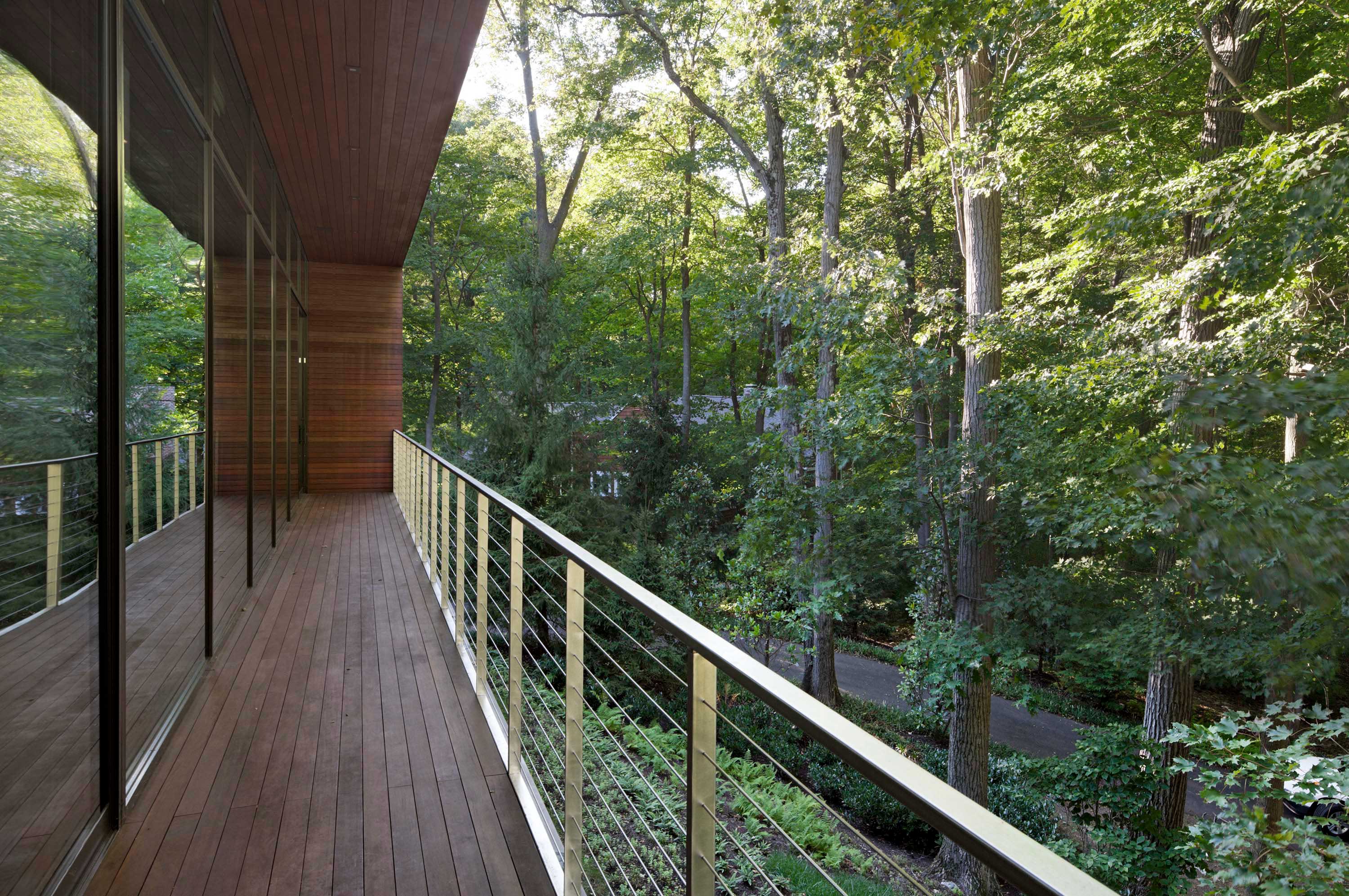 Exterior photo of the New Canaan Residence by Specht Novak Architects. Shot by Elizabeth Felicella featuring a longitudinal balcony that faces the abundant trees on the perimeter of the home.