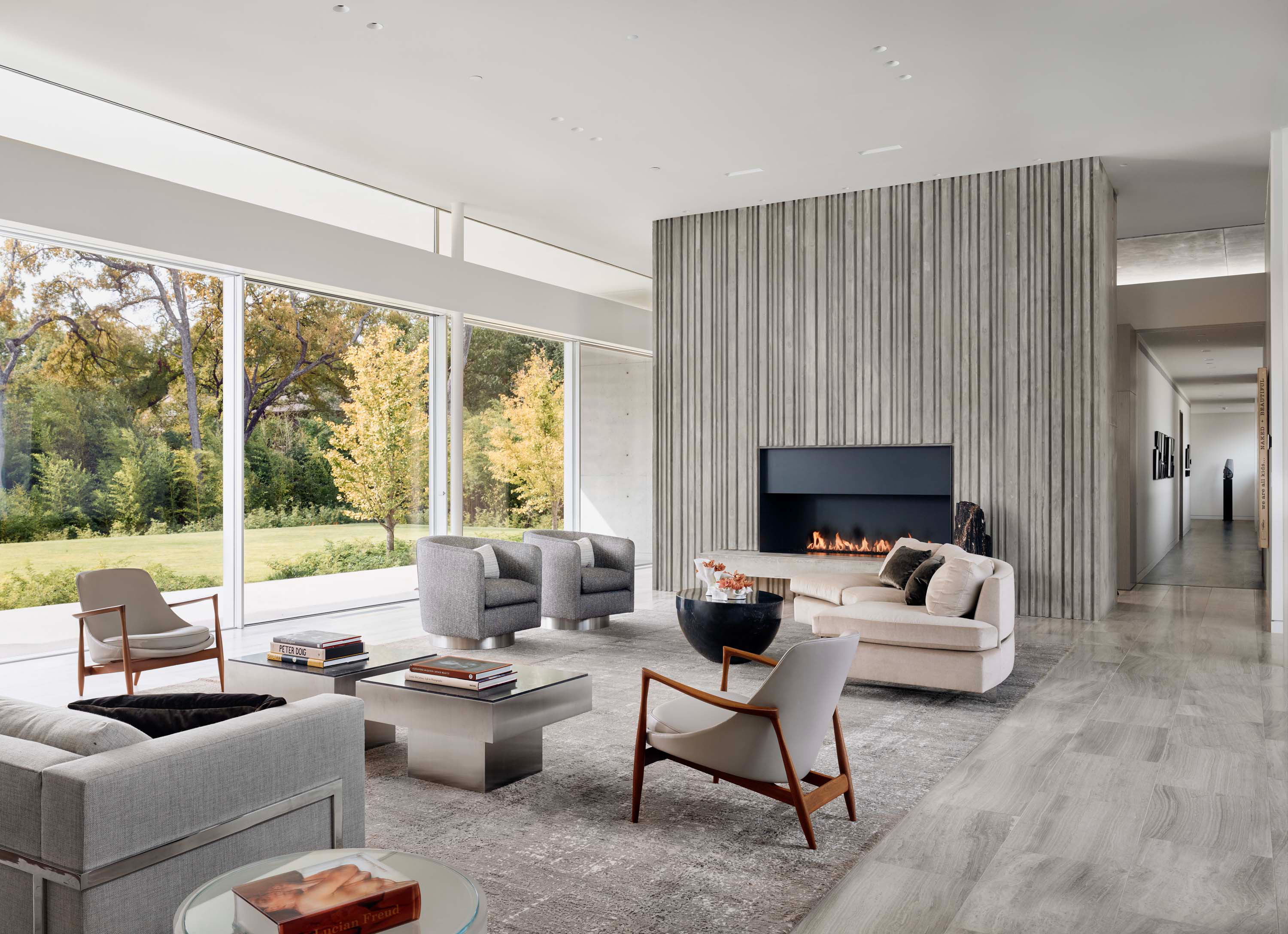 Interior photo of the Preston Hollow Residence by Specht Novak Architects. Shot by Manolo Langis, featuring an expansive living space with fireplace and open views of the yard.