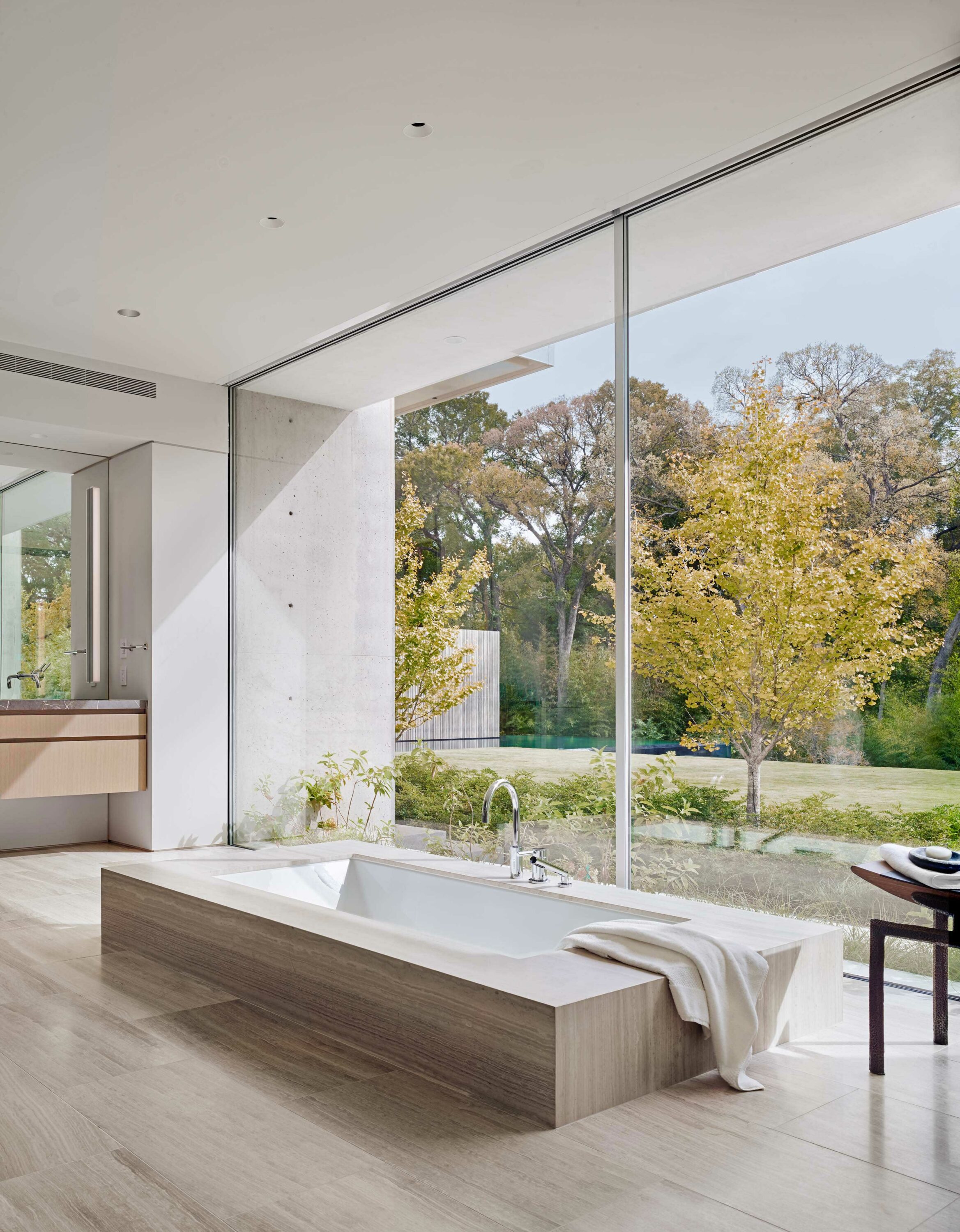 Interior photo of the Preston Hollow Residence by Specht Novak Architects. Shot by Manolo Langis, featuring bathtub, sink, and views of the backyard.