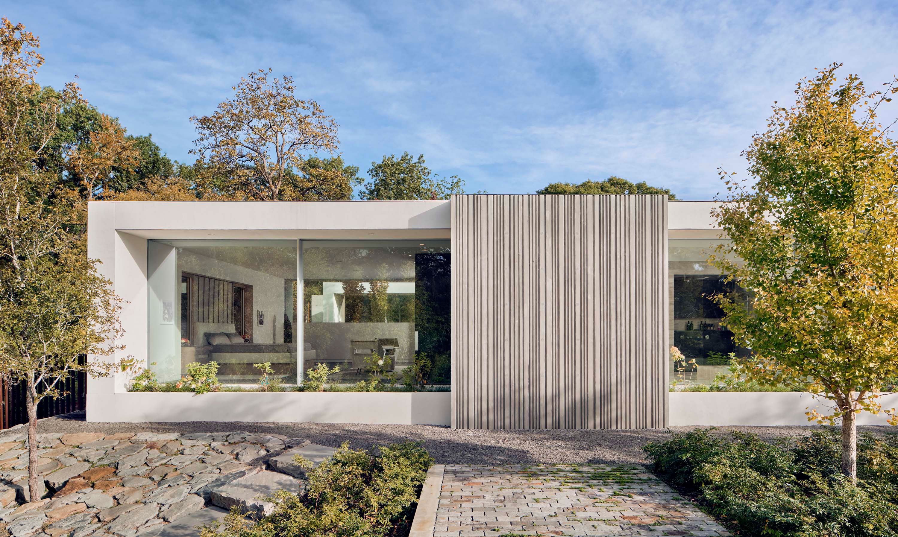 Exterior photo of the Preston Hollow Residence by Specht Novak Architects. Shot at by Manolo Langis, featuring the main bedroom, surrounding trees, and accent concrete wall.