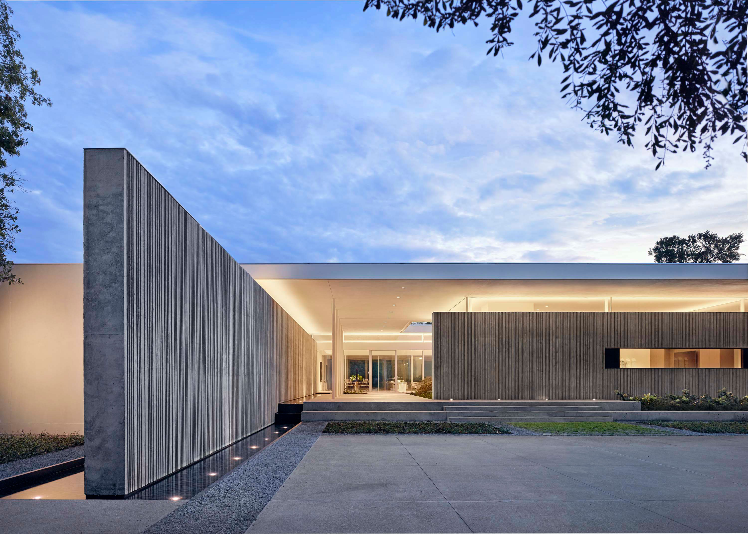 Exterior photo of the Preston Hollow Residence by Specht Novak Architects. Shot in the afternoon by Manolo Langis, featuring the entrance to the home, and monolithic concrete wall.