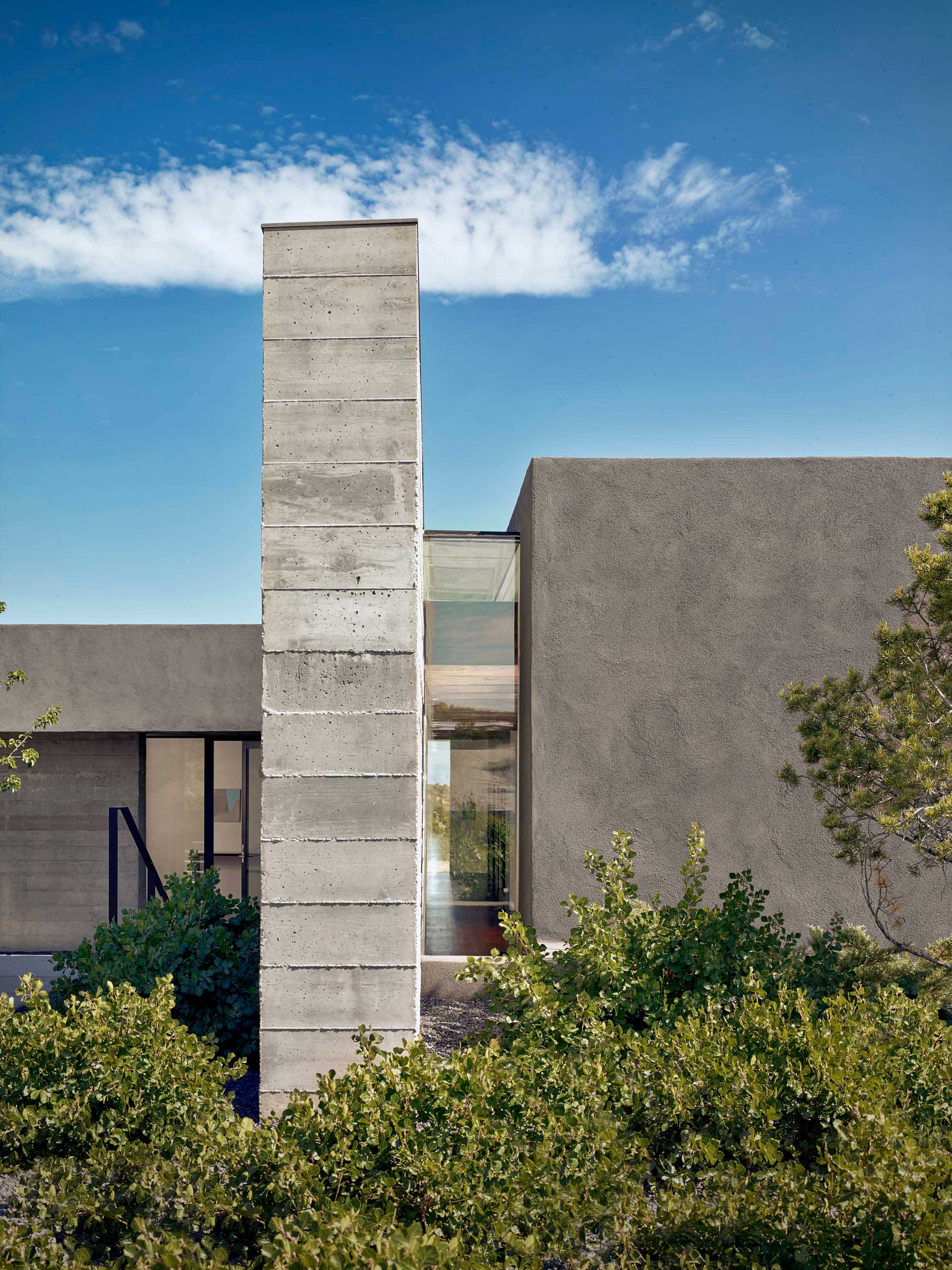 Exterior photo of the Sangre de Cristo House by Specht Novak Architects. Shot by Casey Dunn, featuring the concrete structure surrounded by greenery.