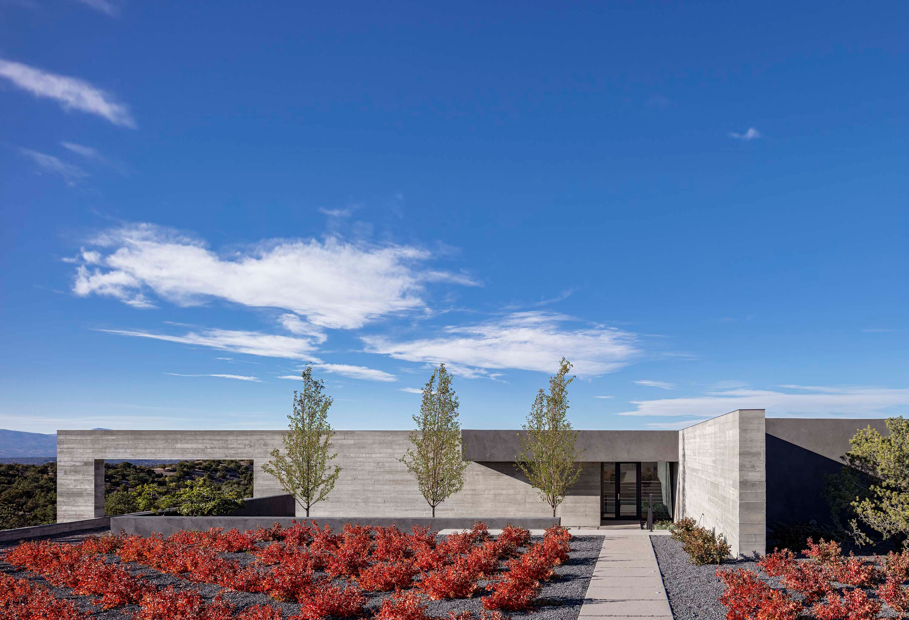 Exterior photo of the Sangre de Cristo House by Specht Novak Architects. Shot by Casey Dunn, featuring a welcoming entryway to the concrete home and its surrounding garden.