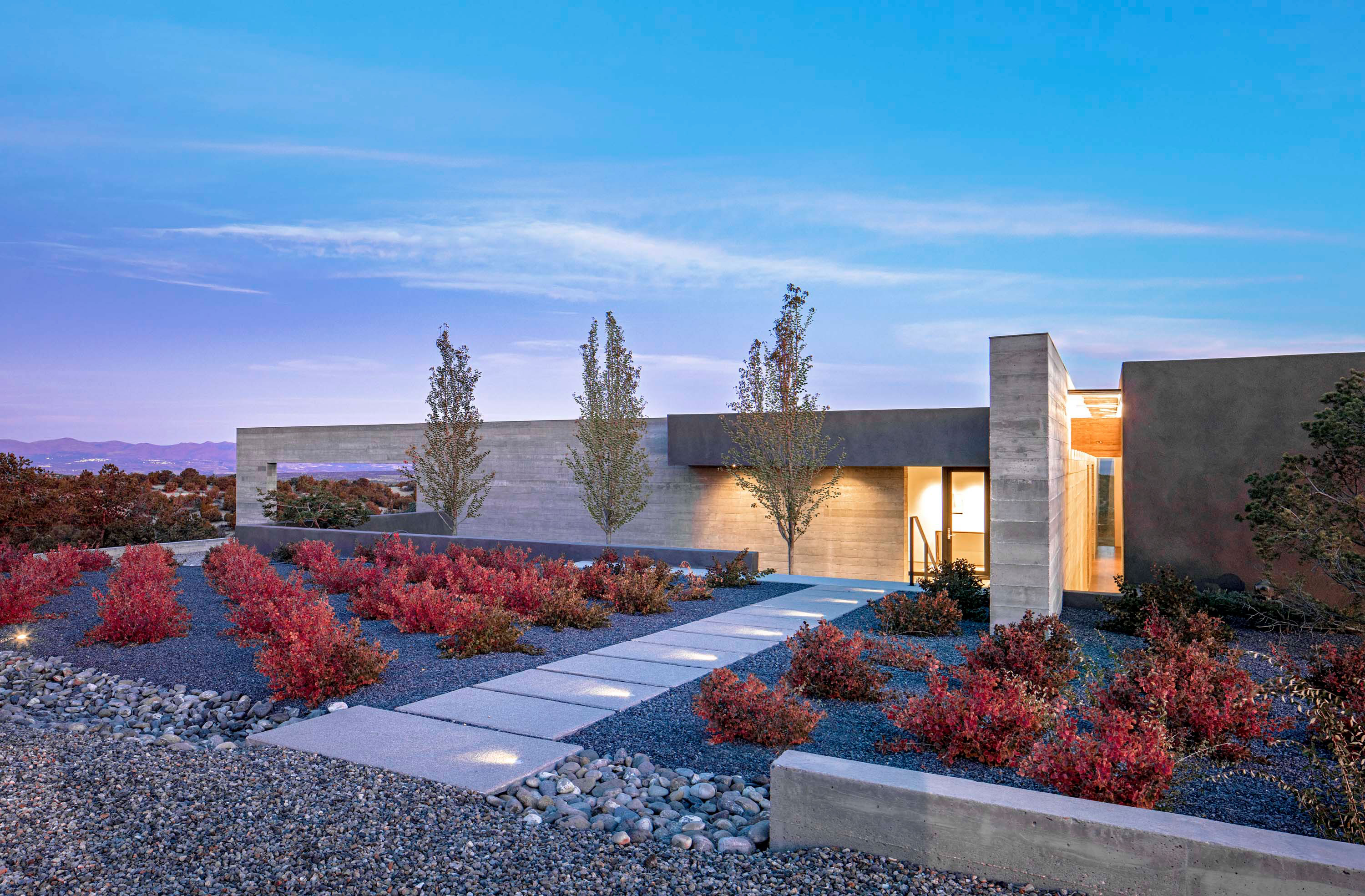 Exterior photo of the Sangre de Cristo House by Specht Novak Architects. Shot by Casey Dunn, featuring a welcoming entryway to the concrete home and its surrounding garden.
