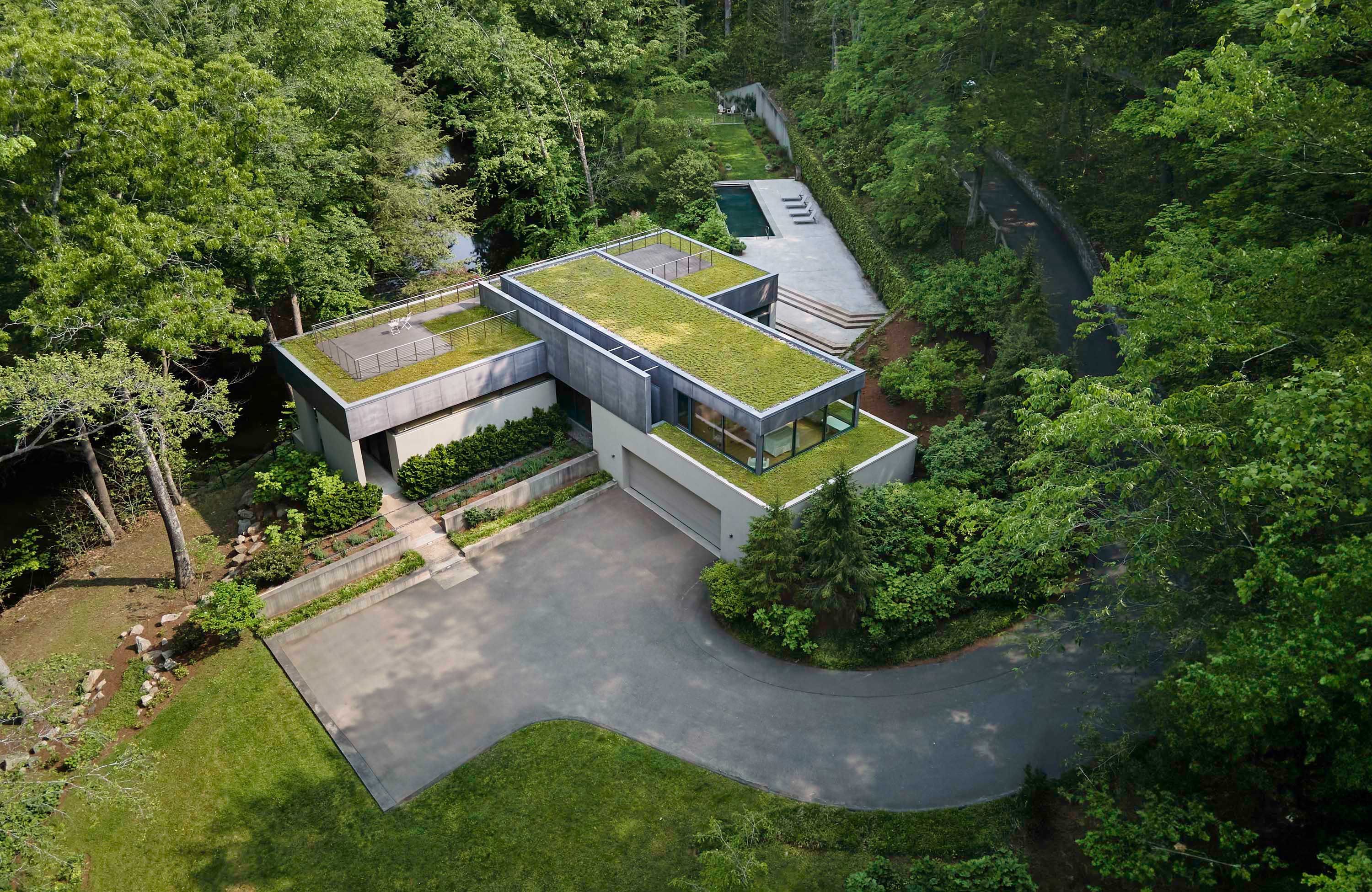 Exterior photo of Weston Residence by Specht Novak Architects. Shot by Jasper Lazor, featuring the concrete and glass home with roof gardens immersed in the landscape from an aerial perspective.