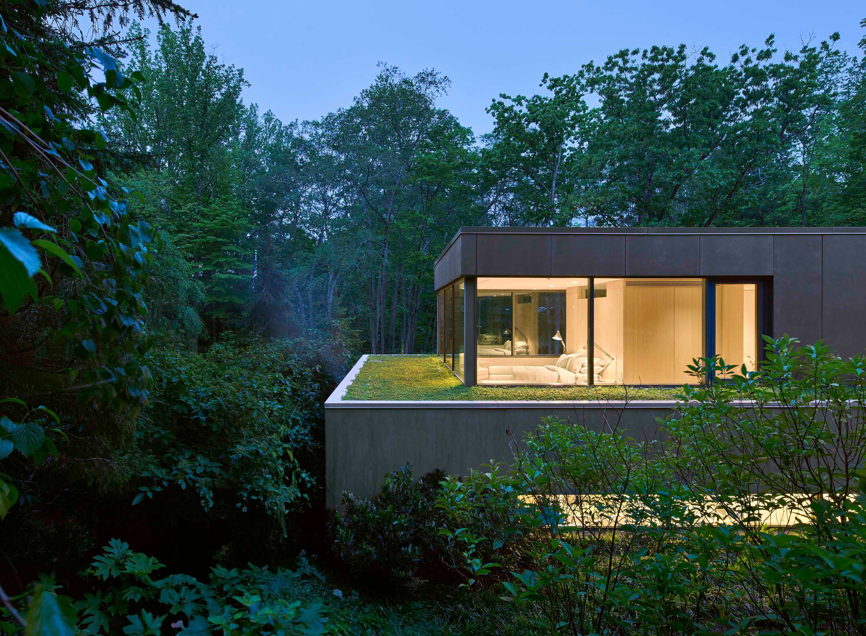 Exterior photo of Weston Residence by Specht Novak Architects. Shot by Jasper Lazor, featuring the main bedroom in a corner of the home with glass walls that open the view to the surrounding nature.