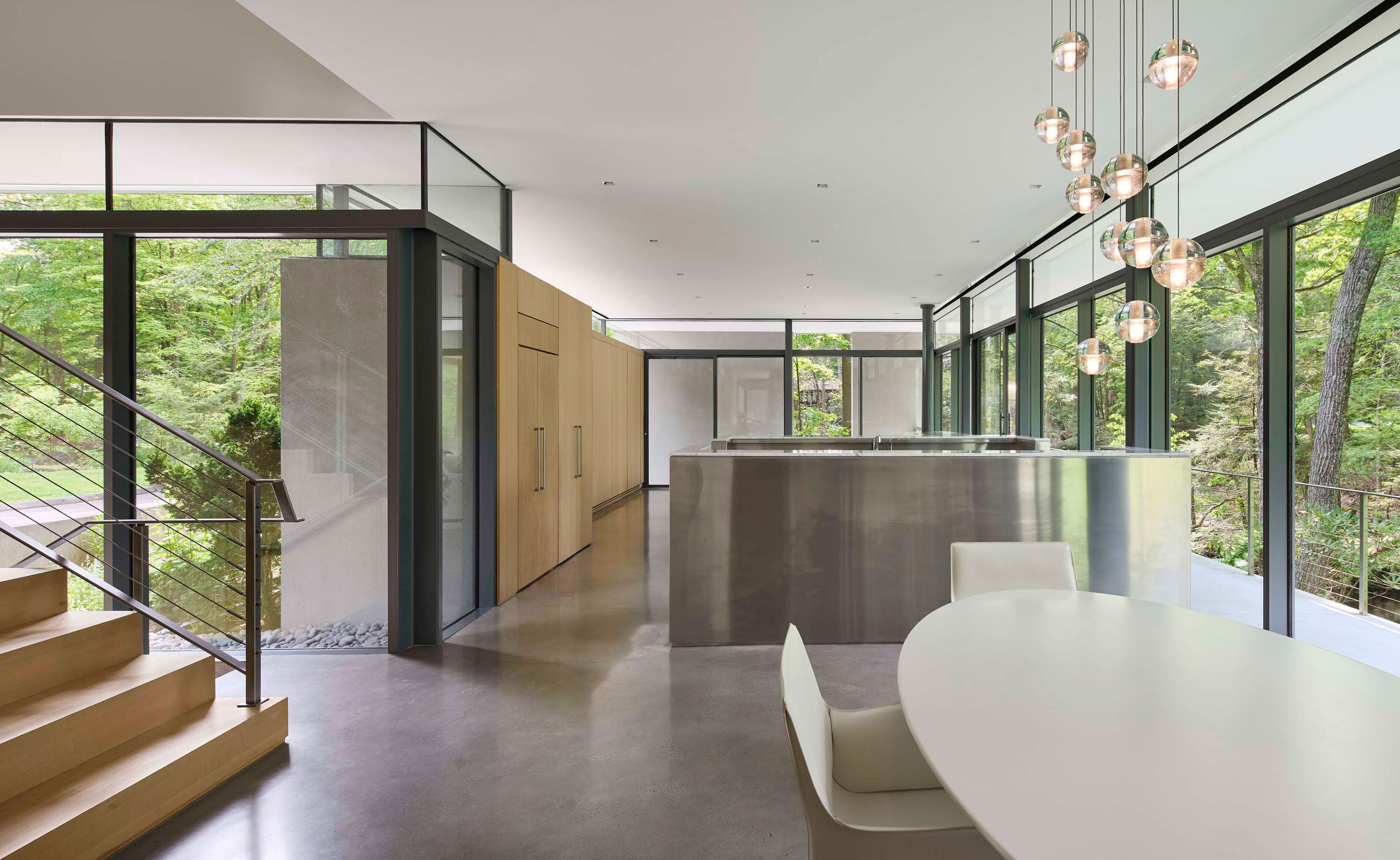 Interior photo of Weston Residence by Specht Novak Architects. Shot by Jasper Lazor, featuring a dining area, modern chandelier, and stairs to upper level.