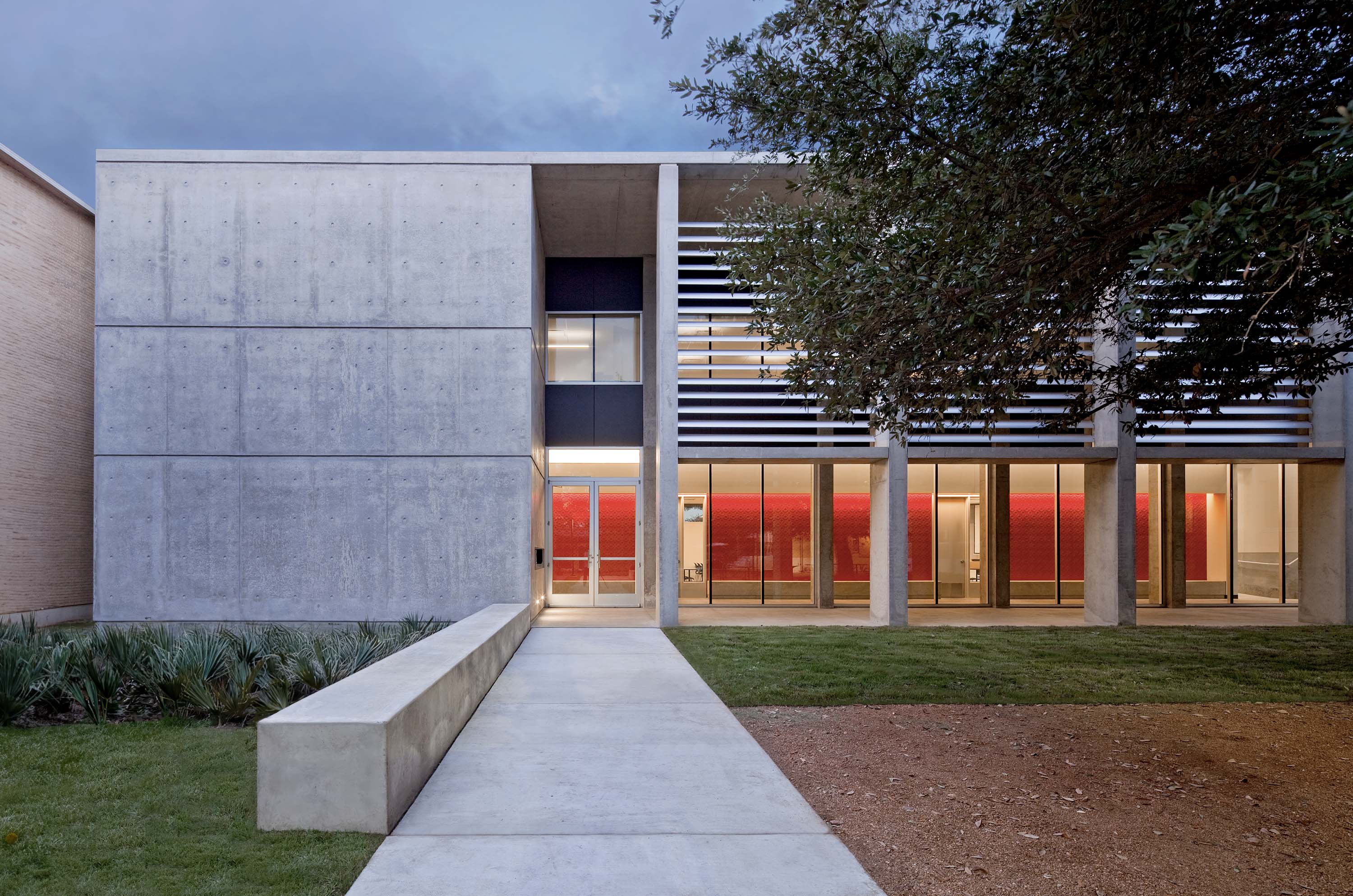 Entryway exterior shot of Doyle Hall by Specht Novak Architects, showcase the exposed concrete and horizontal slats over the windows. Shot by Taggart Sorensen.
