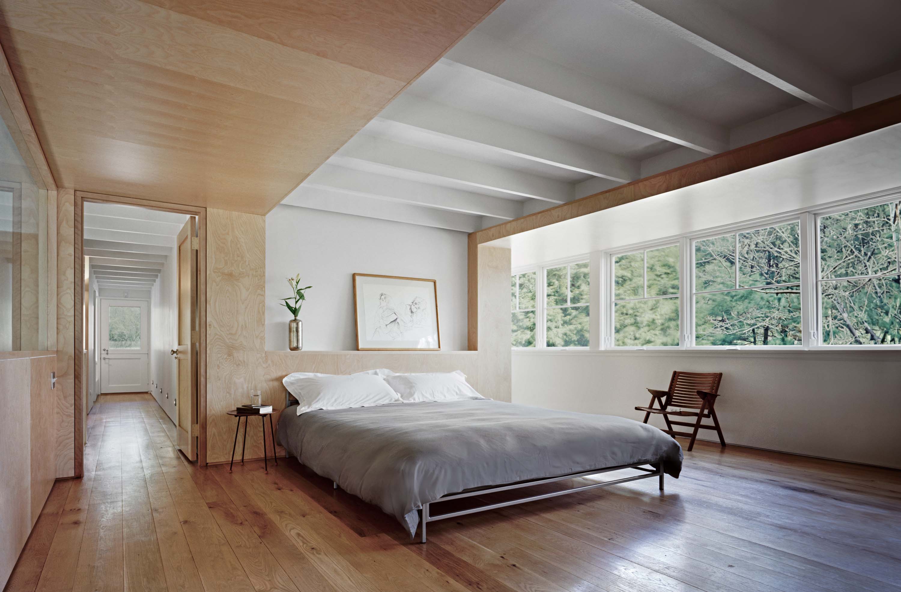 Master bedroom of the Modern Barn by Specht Novak Architects, showcasing the custom maple plywood adding contrast against the exposed white ceiling beams. Shot by Michael Moran.