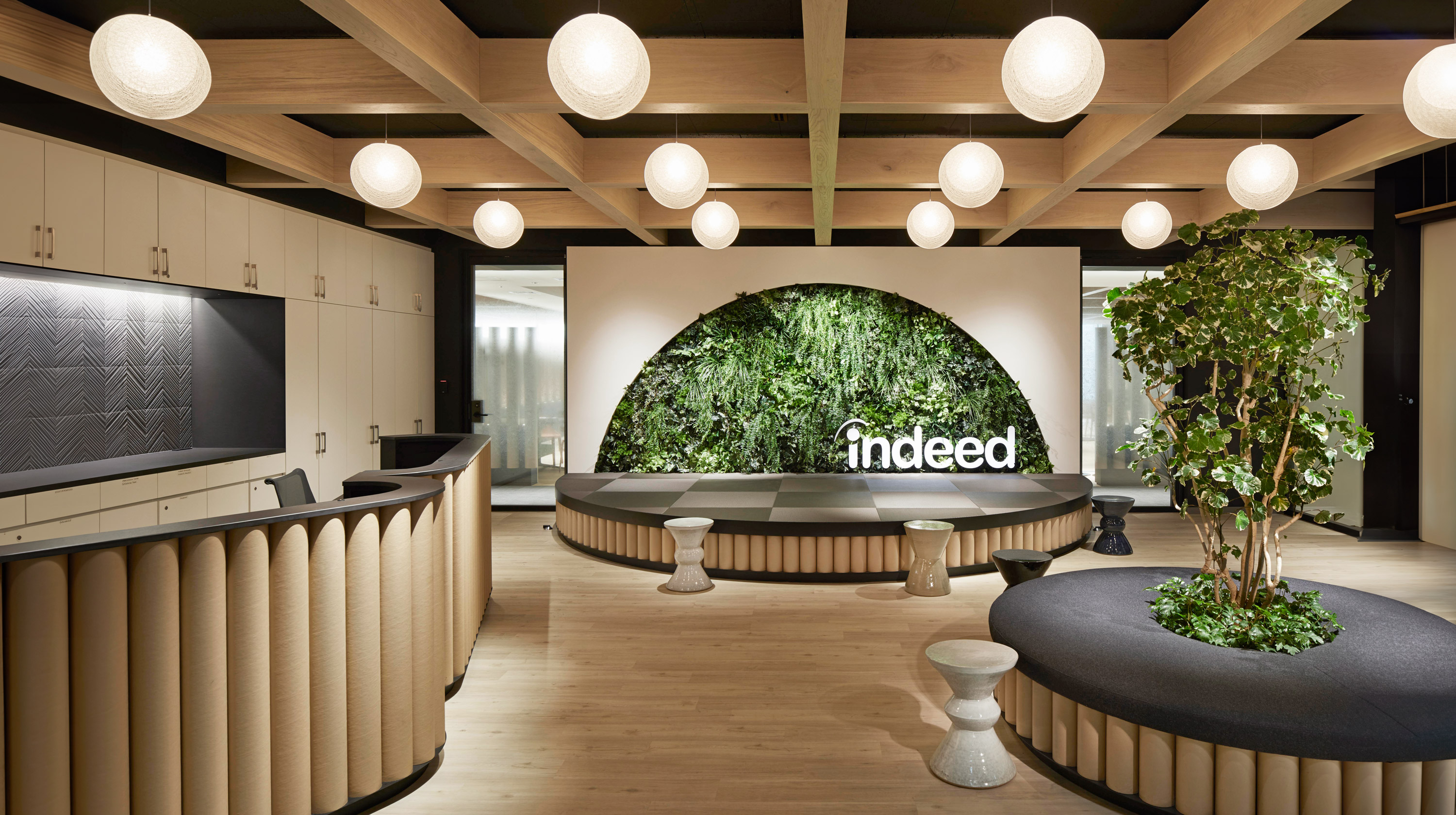 Reception desk featuring welcoming wood and greenery of Indeed.com Tokyo, Japan by Specht Novak Architects.